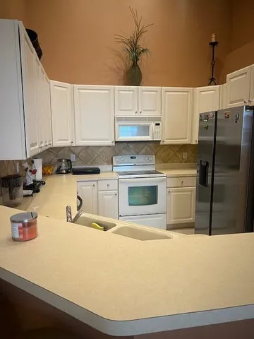a kitchen with stainless steel appliances granite countertop a sink a stove and white cabinets