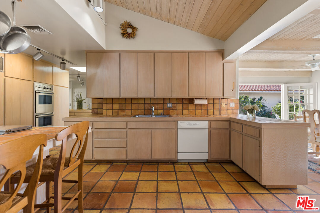 635 North Bonhill Road Los Angeles, CA 90049 - Photo 7 of 19 a kitchen with stainless steel appliances granite countertop a sink and cabinets