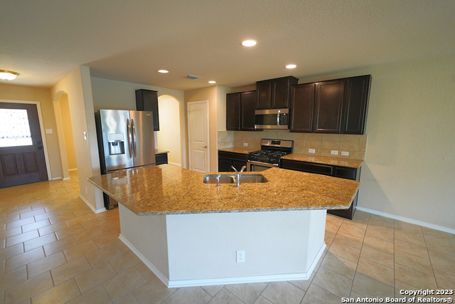 12316 Erstein Valley Schertz, TX 78154 - Photo 14 of 50 a room with kitchen island a sink a stove and a refrigerator