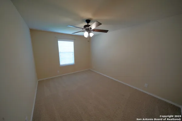 an empty room with windows and fan