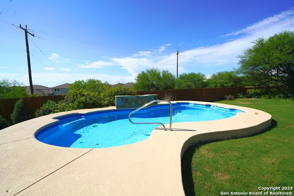 a view of a swimming pool with a yard and plants