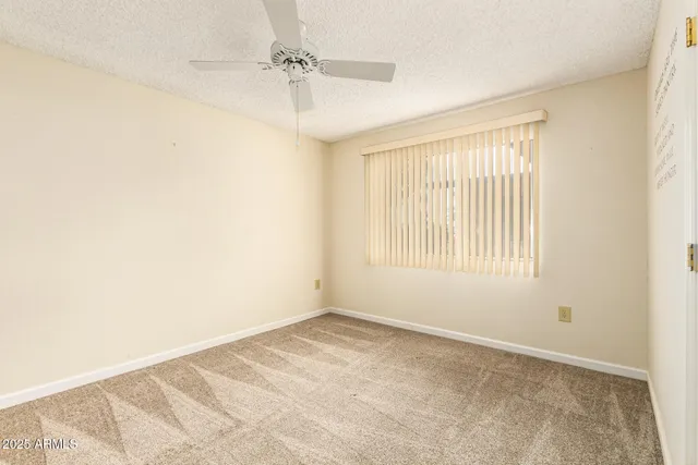 a view of a big room with windows and chandelier fan