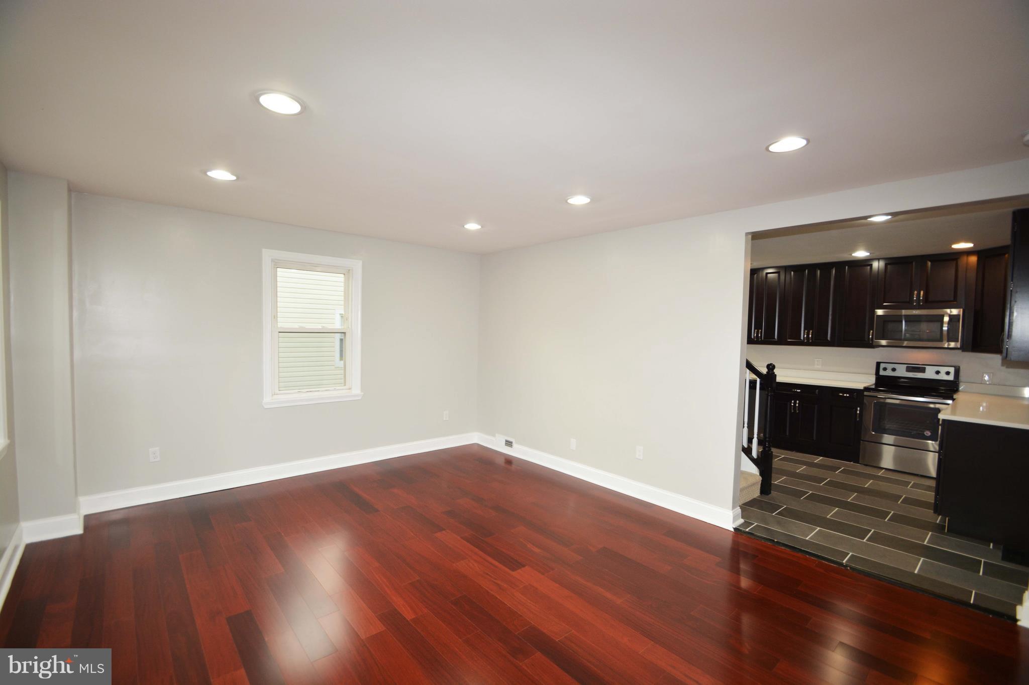 7116 Marston Road Baltimore, MD 21207 - Photo 20 of 30 an empty room with wooden floor and entrance to kitchen