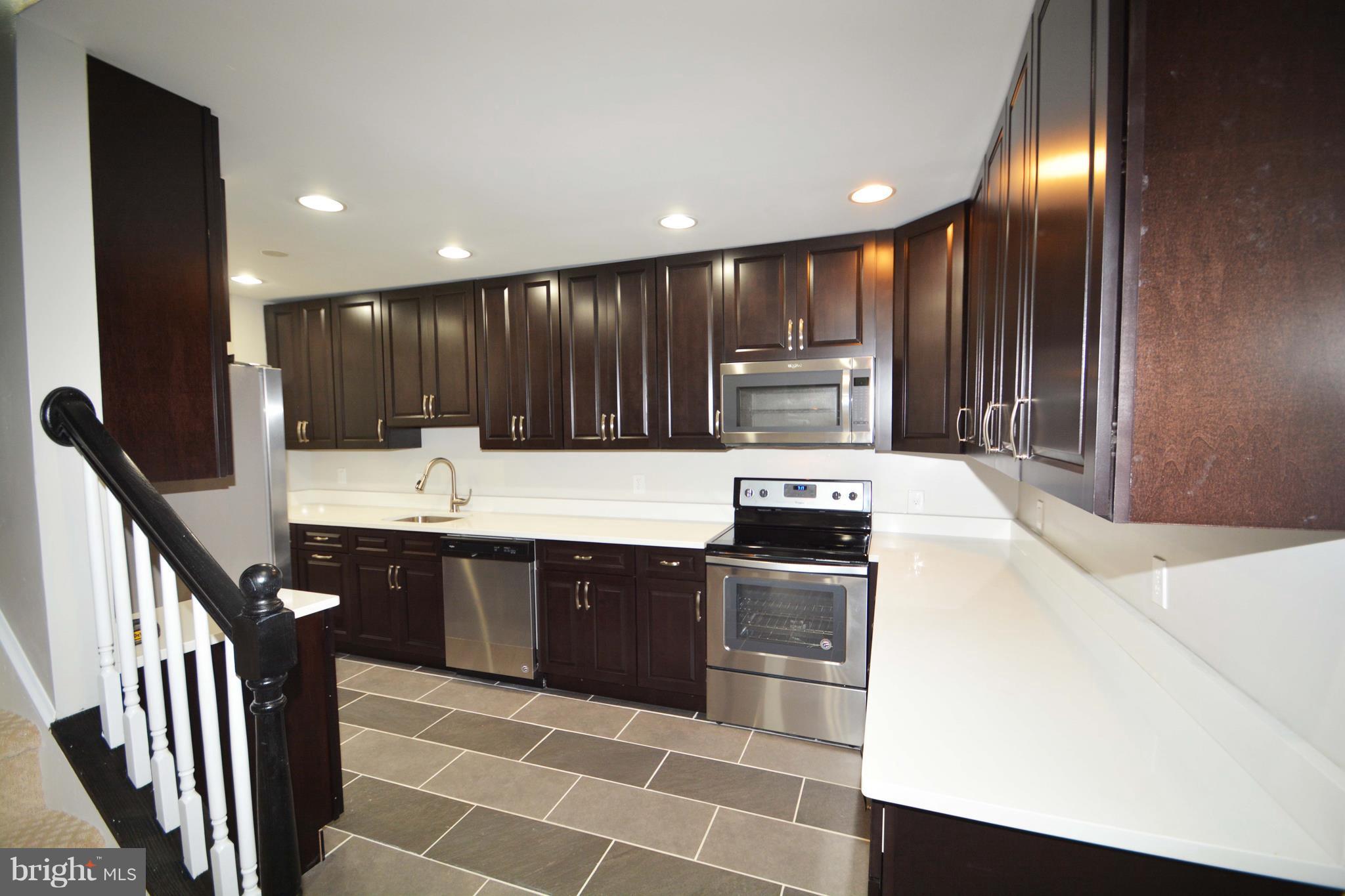 7116 Marston Road Baltimore, MD 21207 - Photo 23 of 30 a kitchen with kitchen island granite countertop wooden cabinets a sink and dishwasher