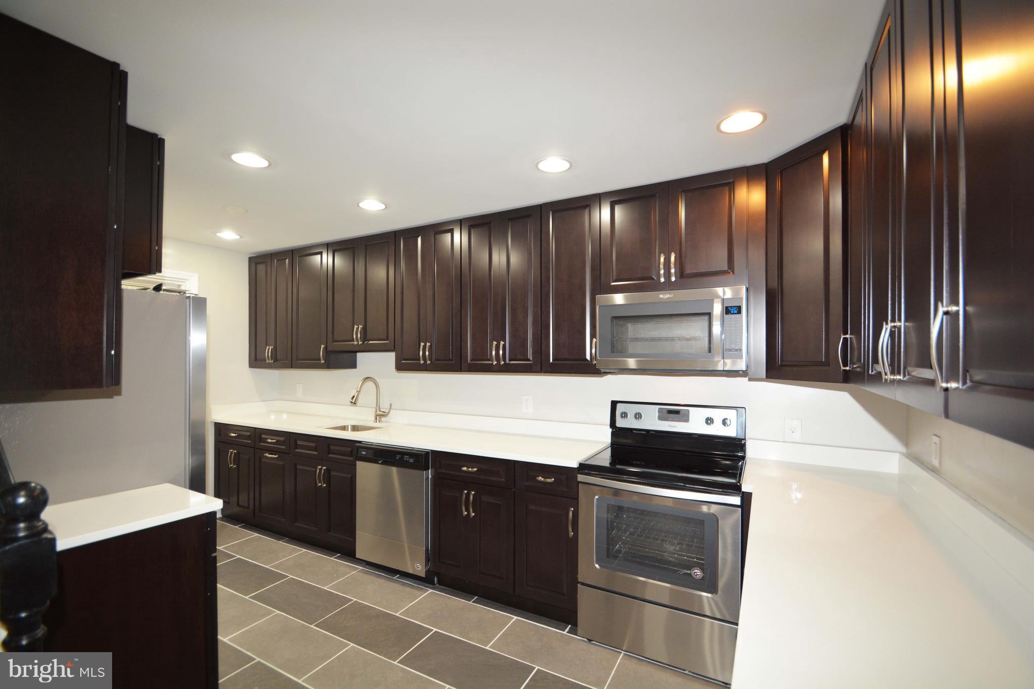 7116 Marston Road Baltimore, MD 21207 - Photo 26 of 30 a kitchen with kitchen island granite countertop wooden cabinets and stainless steel appliances