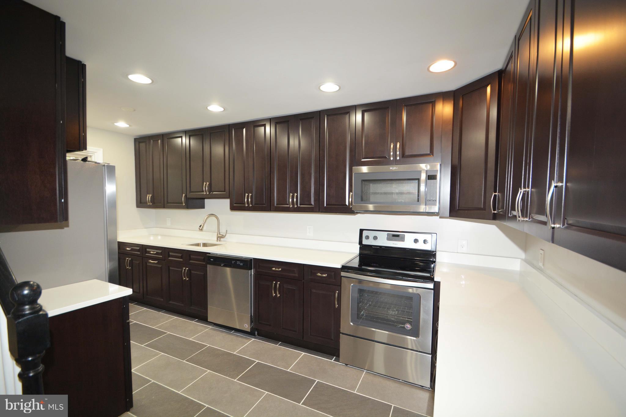 7116 Marston Road Baltimore, MD 21207 - Photo 27 of 30 a kitchen with kitchen island granite countertop wooden cabinets a stove top oven and sink