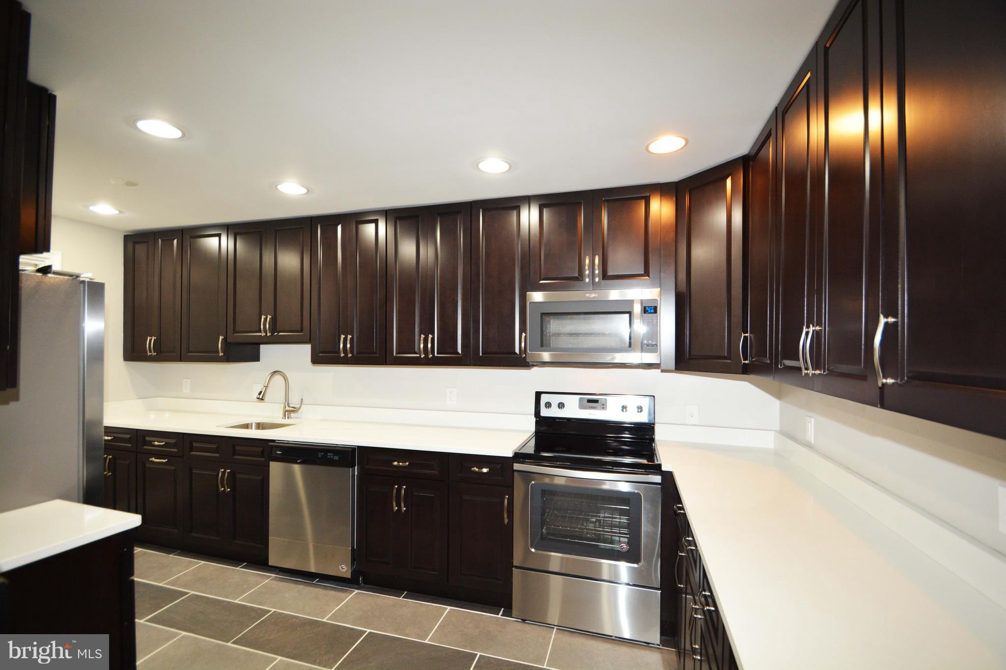 7116 Marston Road Baltimore, MD 21207 - Photo 6 of 30 a kitchen with kitchen island granite countertop wooden cabinets and stainless steel appliances