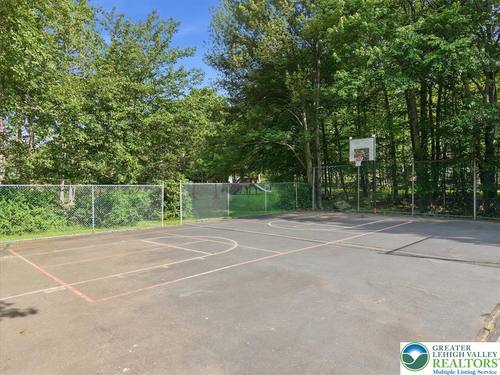 143 Logger Road Canadensis, PA 18325 - Photo 29 of 32 An outdoor basketball court bordered by a chain-link fence and lush green trees awaits recreational fun.