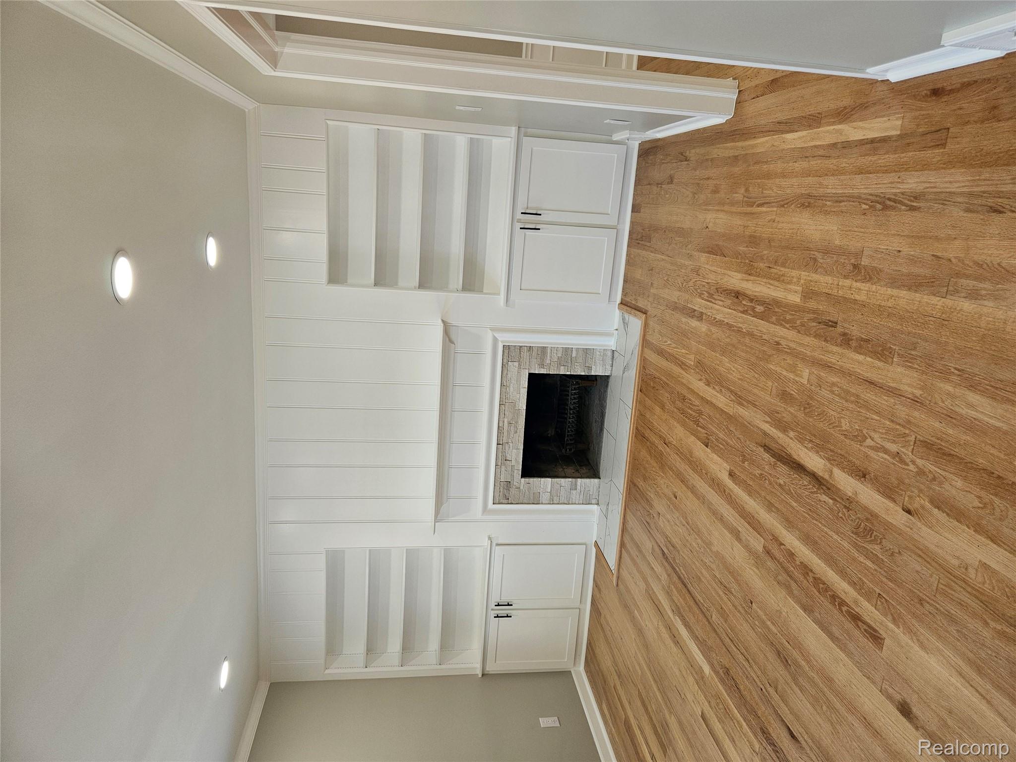 17345 Annchester Road Detroit, MI 48219 - Photo 4 of 22 Unfurnished living room featuring ornamental molding, built in features, light wood-style floors, recessed lighting, and a fireplace