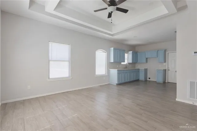 wooden floor in an empty room with a window and a kitchen