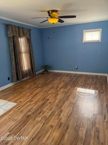 a view of empty room with wooden floor and fan
