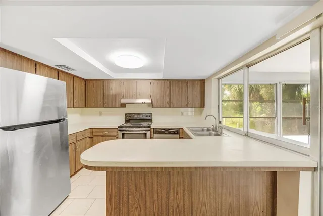 a kitchen with stainless steel appliances a refrigerator a sink a stove and white cabinets with wooden floor