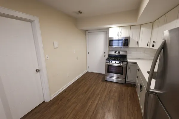 a kitchen with kitchen island wooden floors appliances and cabinets