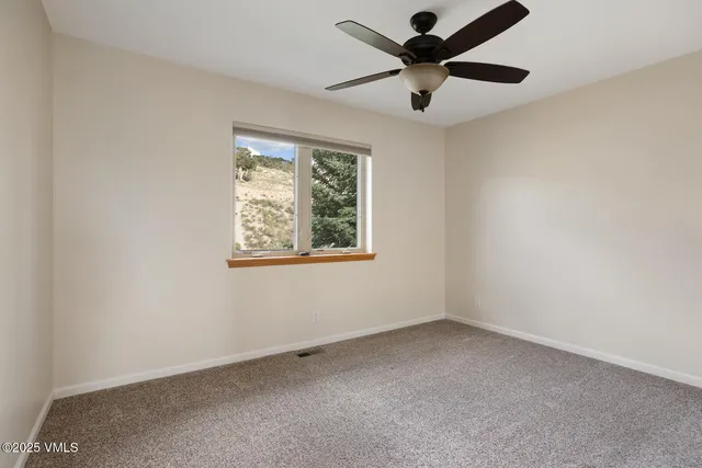 an empty room with a window and a fan