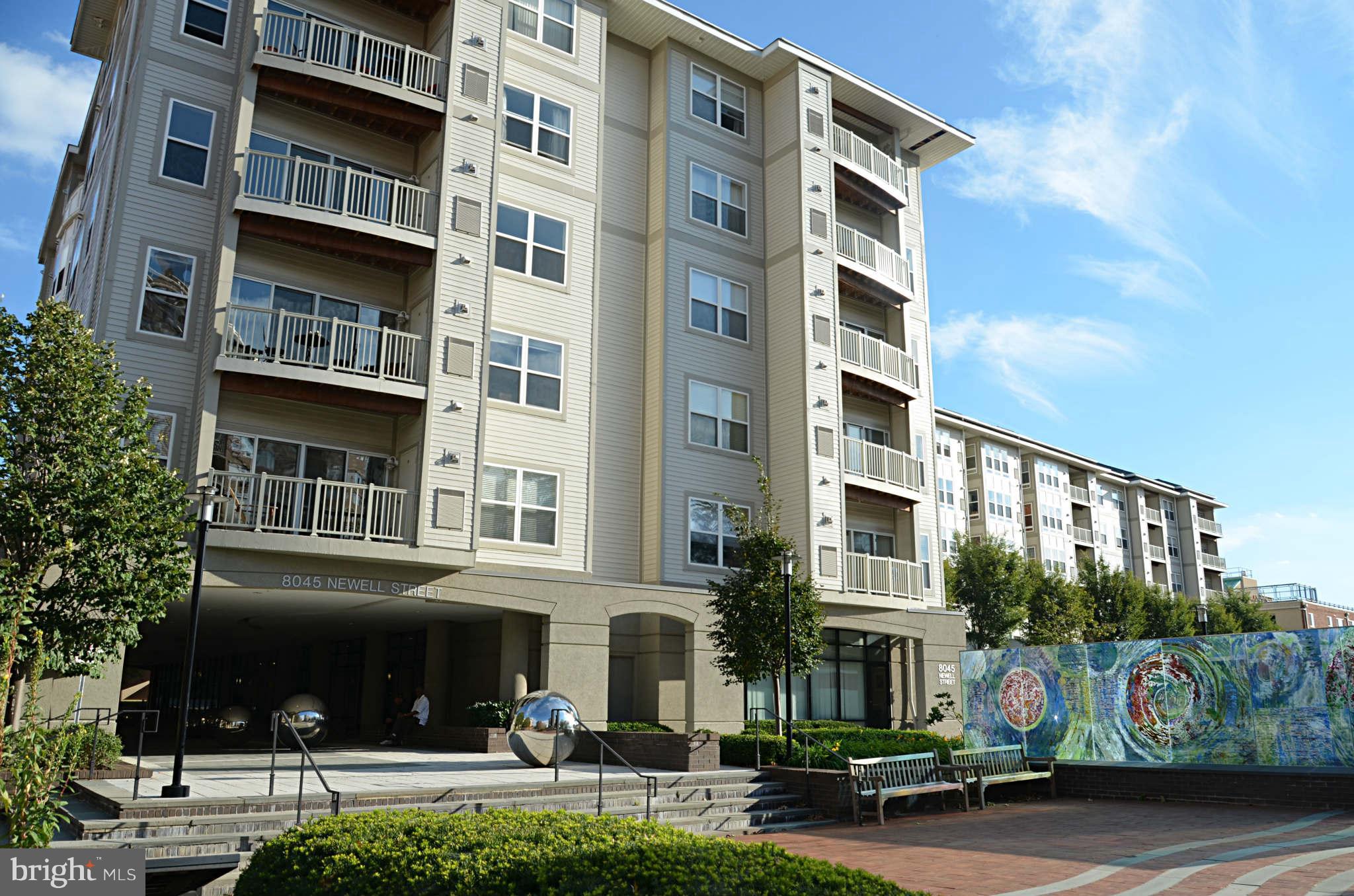 a front view of multi story residential apartment building with yard and retail shops