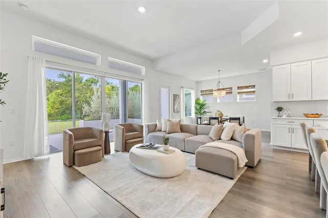 a kitchen with stainless steel appliances granite countertop a refrigerator a sink a stove a dining table and chairs with wooden floor