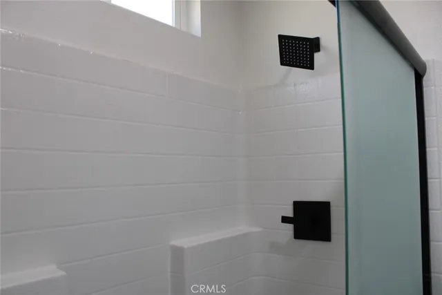 a bathroom with a shower and a tiled wall