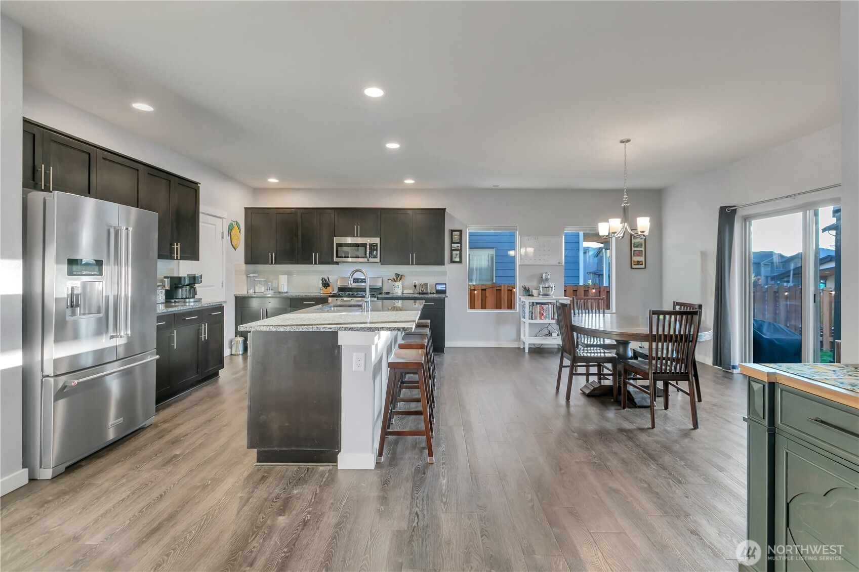 291 South Sergeant Street Buckley, WA 98321 - Photo 10 of 38 a kitchen with stainless steel appliances granite countertop a refrigerator a stove top oven a sink dishwasher a dining table and chairs with wooden floor