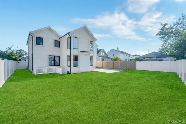 a view of a back yard with an tree and a fence