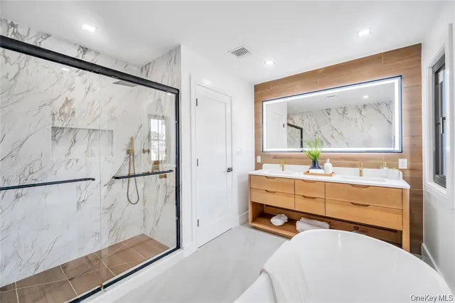 a bathroom with a tub and a double vanity sink mirror