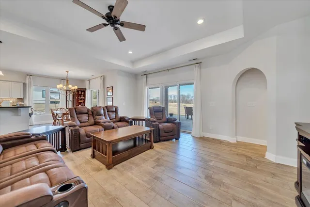 a living room with furniture a ceiling fan a lamp and a window
