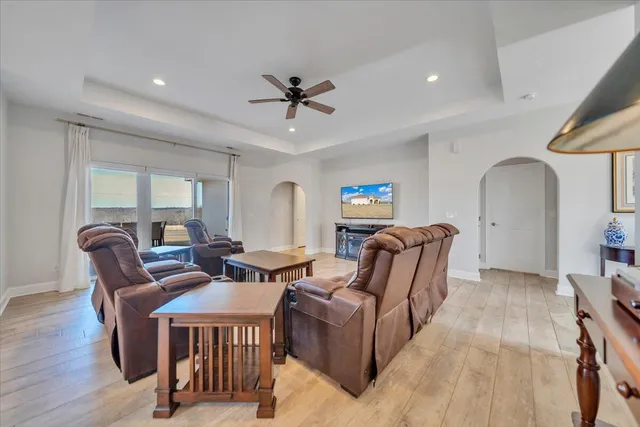 a living room with furniture a flat screen tv and a ceiling fan