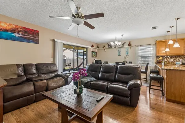 a living room with furniture kitchen view and a chandelier