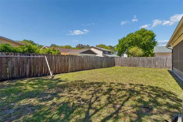 a view of a backyard with a fence and tree