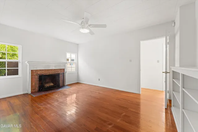 an empty room with windows fireplace and wooden floor