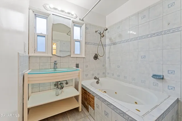 a bathroom with a tub sink a mirror and a shower