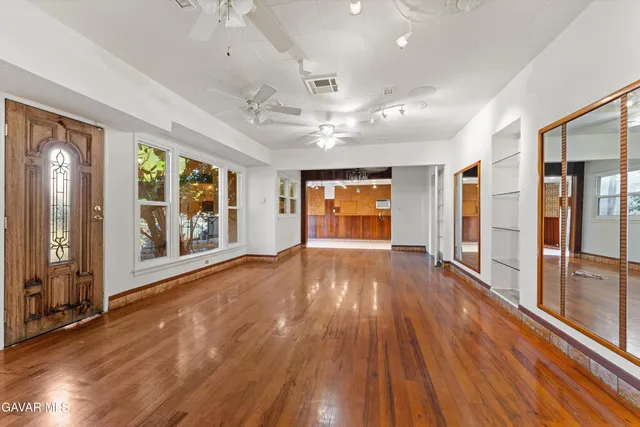 a view of empty room with wooden floor and fan