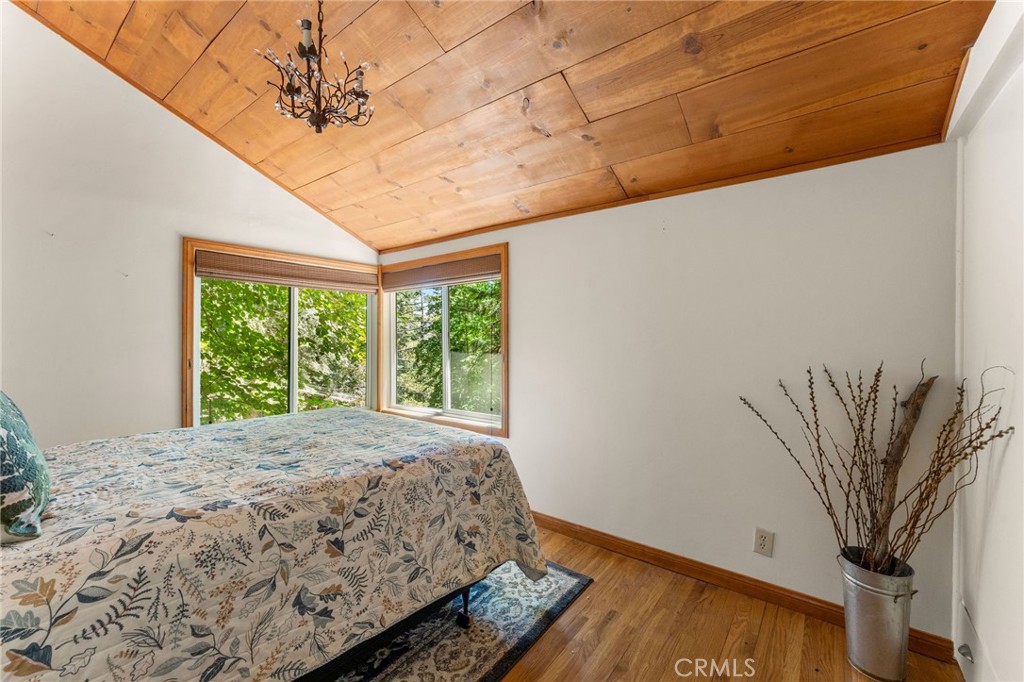 816 Fern Road Lake Arrowhead, CA 92385 - Photo 32 of 35 a bedroom with a large bed and a chandelier