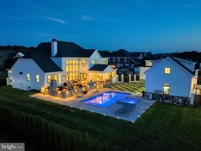 a large kitchen with stainless steel appliances kitchen island granite countertop a refrigerator a stove a sink and a dining table with wooden floor