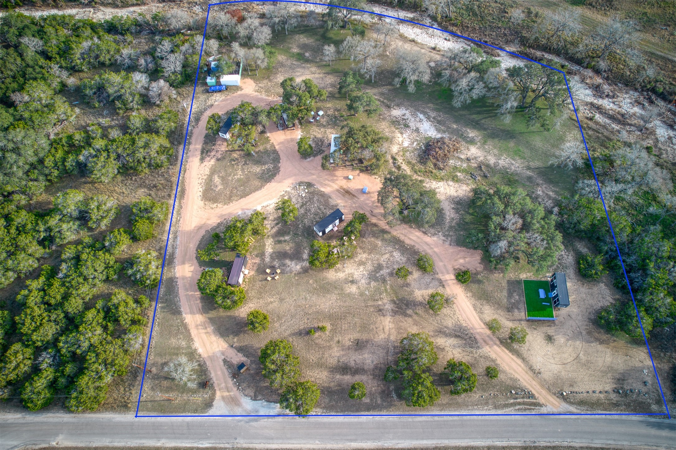 Expansive acreage with multiple structures, natural tree coverage, and a defined boundary