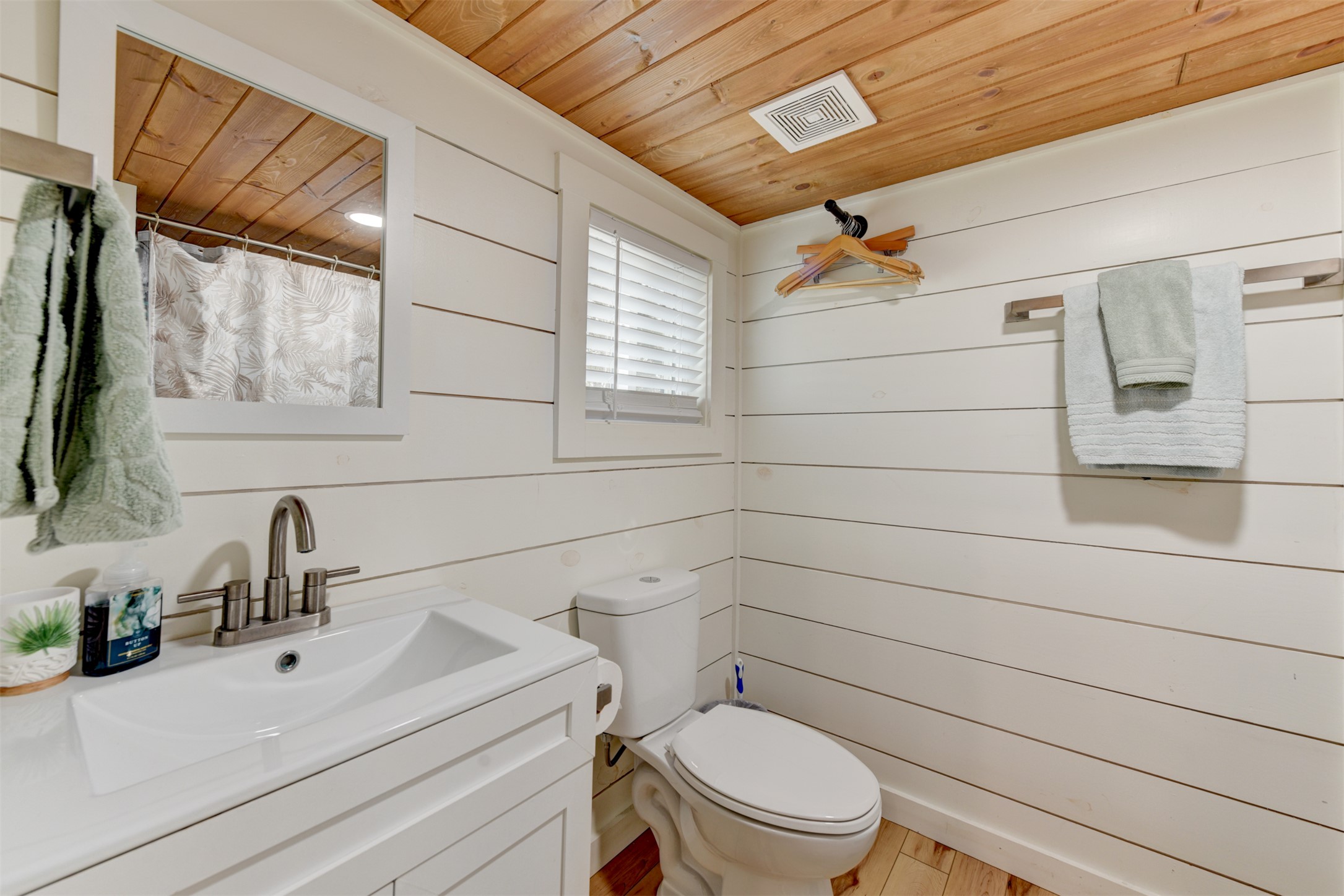 1156 Narrows Road Blanco, TX 78606 - Photo 15 of 40 Bathroom featuring a white vanity with an integrated rectangular sink and brushed nickel faucet, wood-finish flooring, white shiplap walls, a wood-plank ceiling, and a window with white blinds