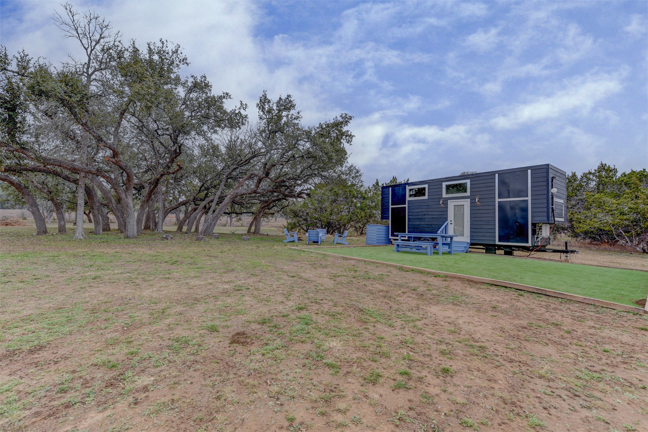 1156 Narrows Road Blanco, TX 78606 - Photo 2 of 40 Modern tiny home exterior with dark siding, multiple windows, and a white entry door