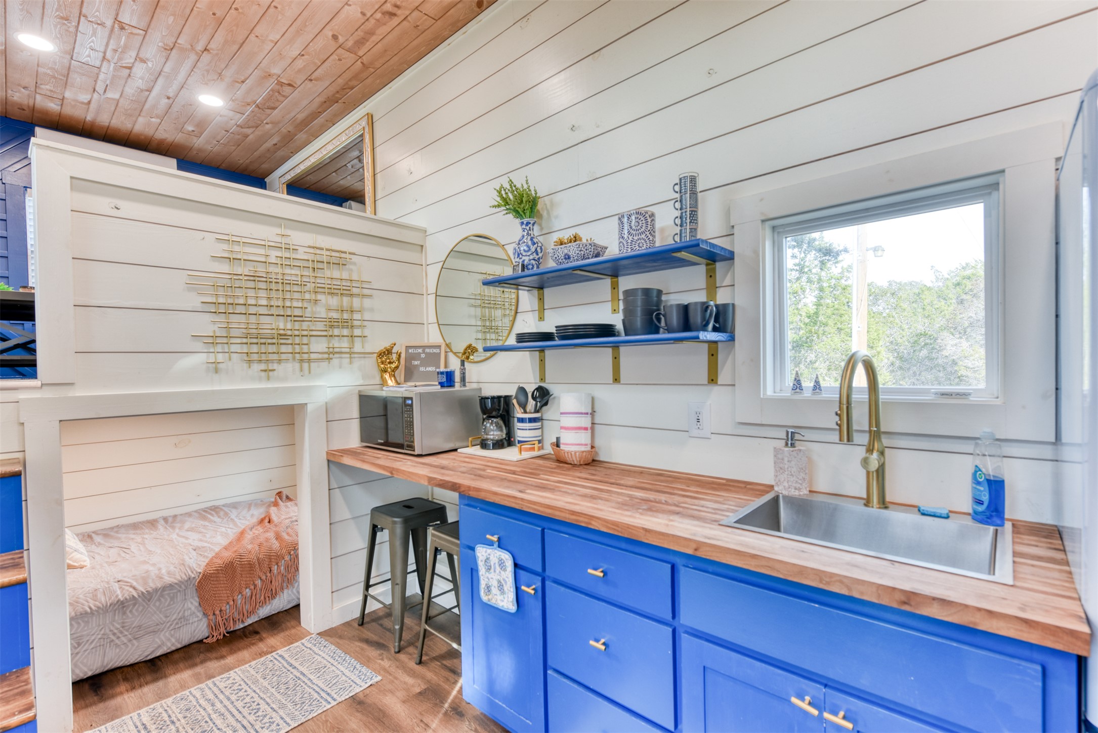 1156 Narrows Road Blanco, TX 78606 - Photo 39 of 40 Compact kitchen area featuring vibrant blue cabinetry, wood-finish countertops, and a stainless steel sink with a brass-tone faucet