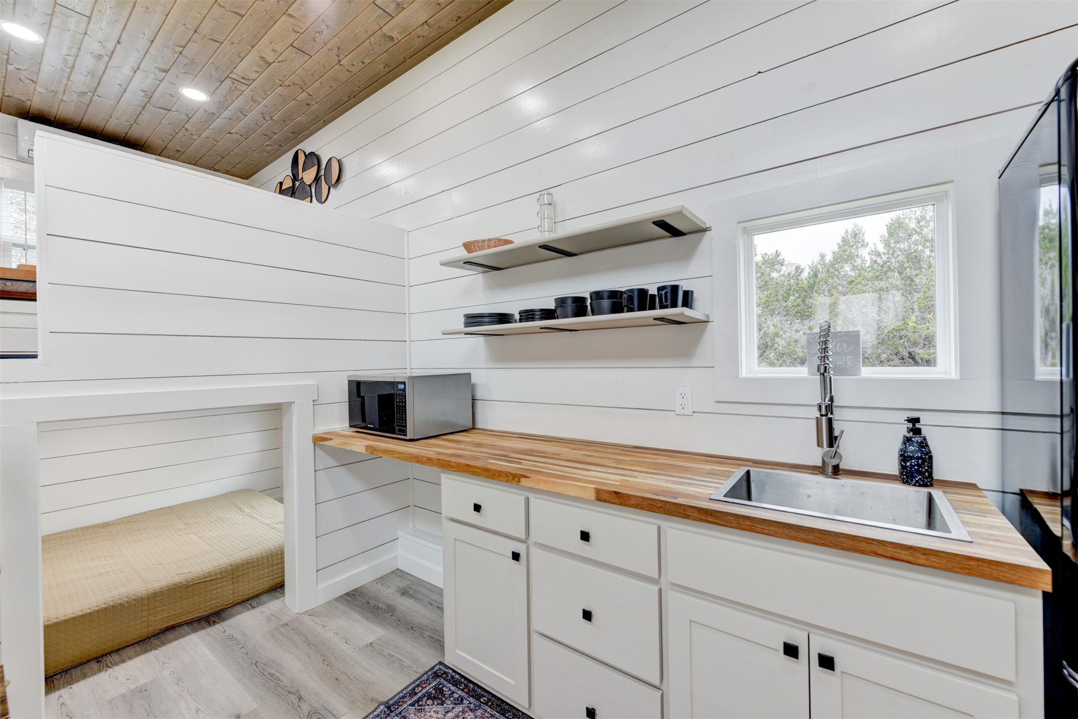 1156 Narrows Road Blanco, TX 78606 - Photo 4 of 40 Kitchen area featuring white shiplap walls, wood-finish countertop with an undermount sink, and open shelving