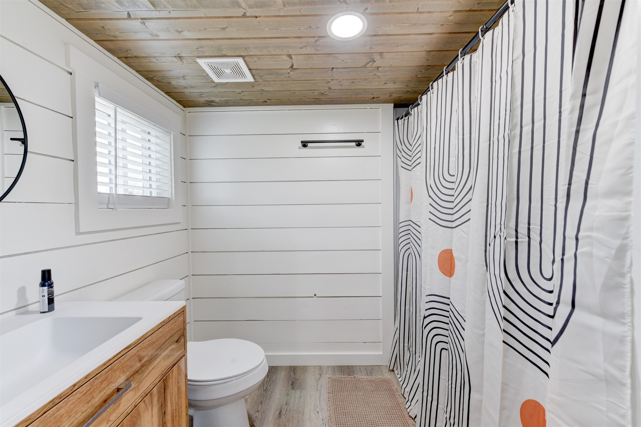 1156 Narrows Road Blanco, TX 78606 - Photo 6 of 40 Bathroom featuring a wood-finish plank ceiling, shiplap wall paneling, a single vanity with a wood-finish cabinet, and a window with horizontal blinds