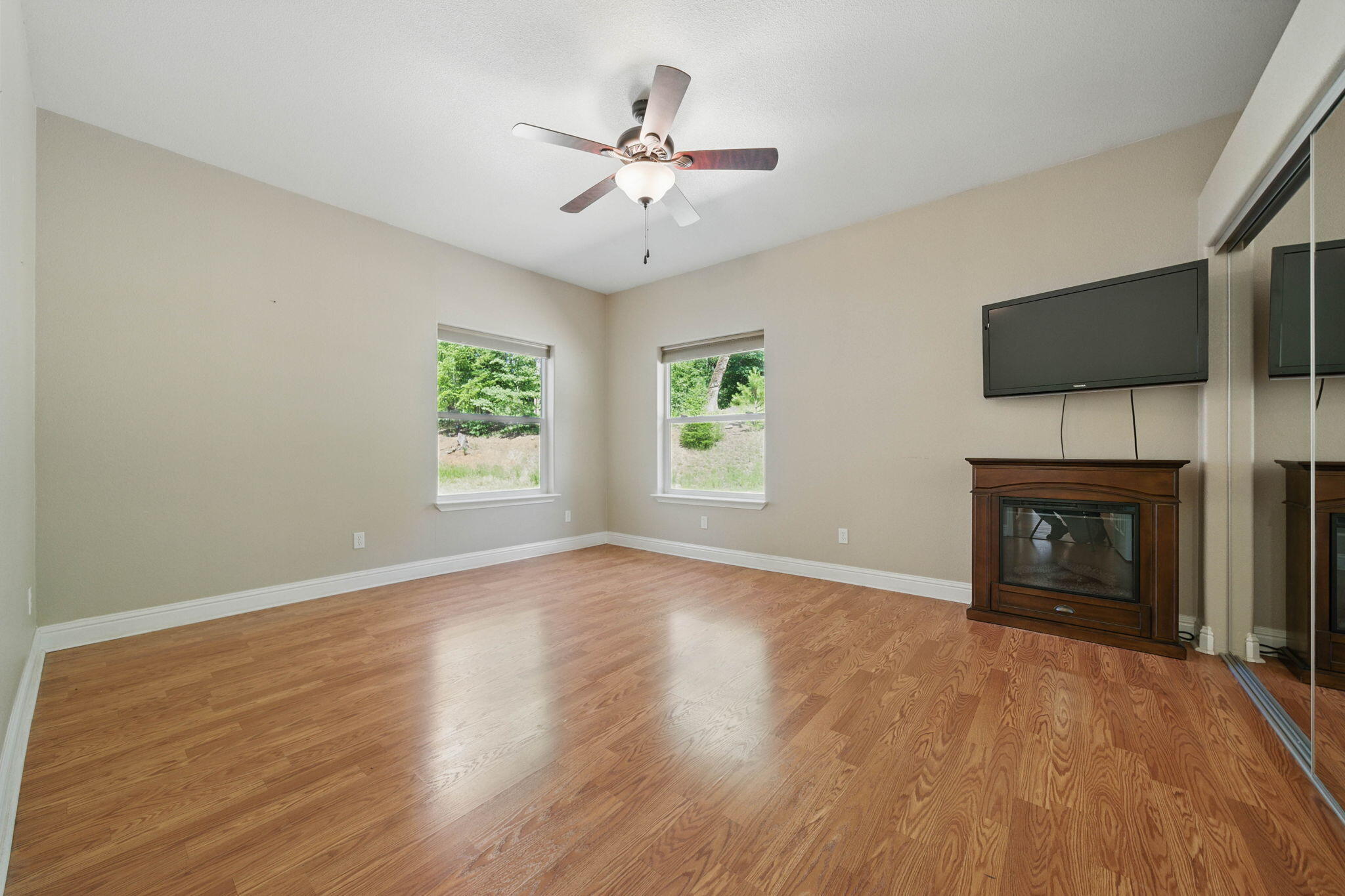 15399 Star Flower Road Oak Run, CA 96069 - Photo 21 of 44 an empty room with windows fireplace and wooden floor