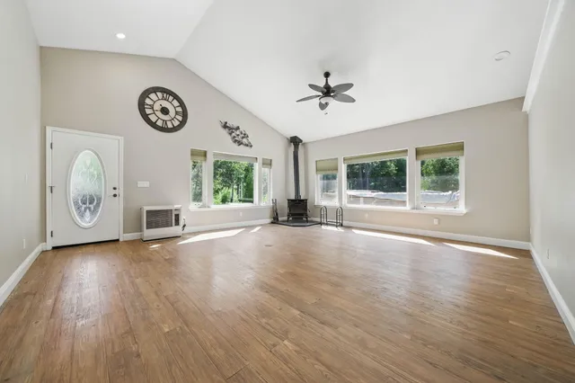 a view of an empty room with a window and wooden floor