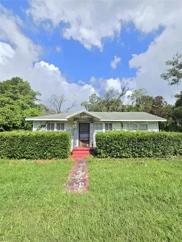 a view of a house with a yard and potted plants