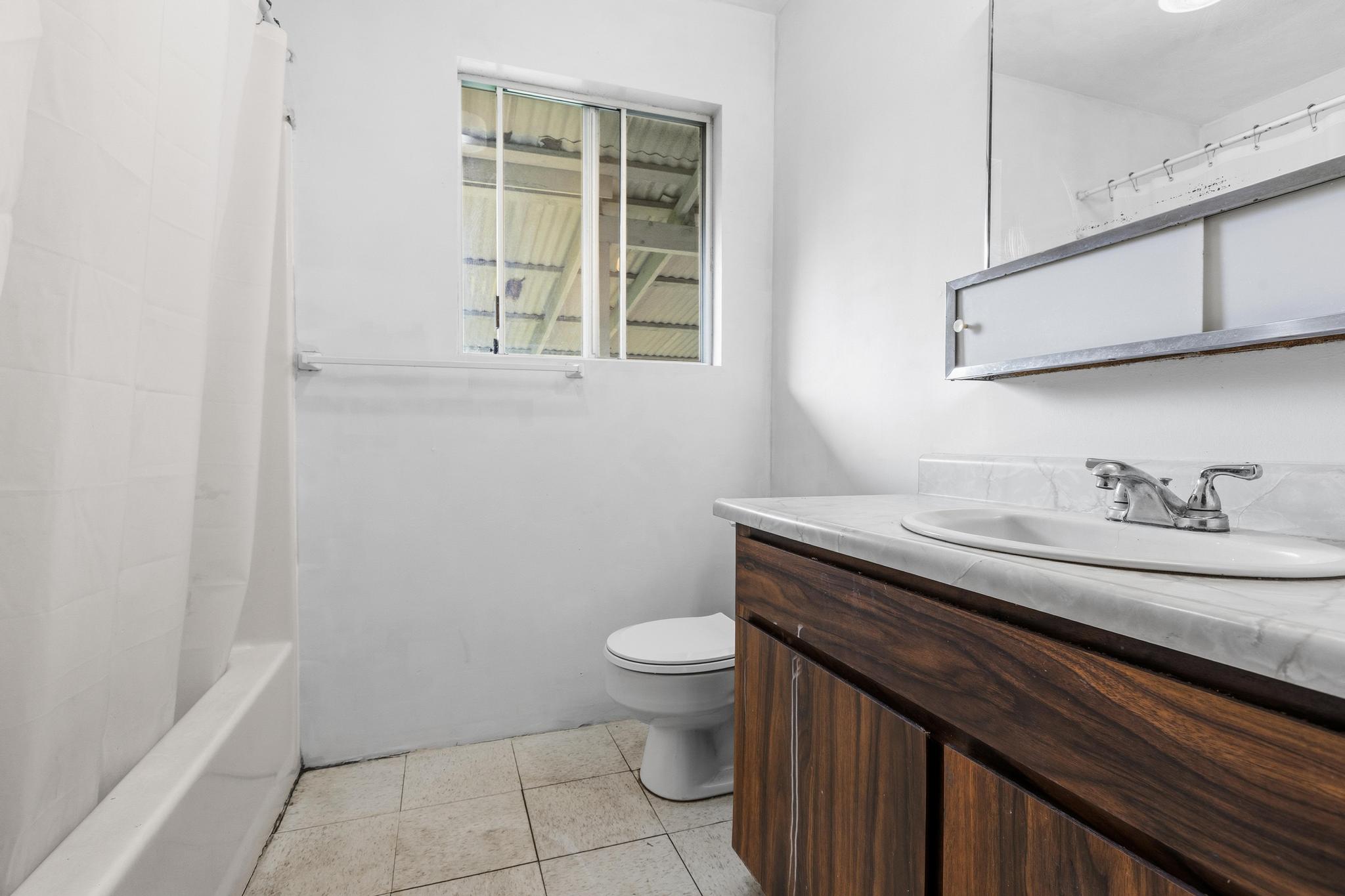 1560 Kilauea Avenue Hilo, HI 96720 - Photo 8 of 29 a bathroom with a granite countertop sink a toilet and a mirror