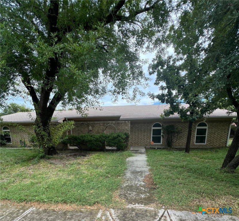 a front view of a house with a garden and trees