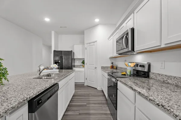 a kitchen with stainless steel appliances granite countertop a sink a stove and a refrigerator with wooden floor