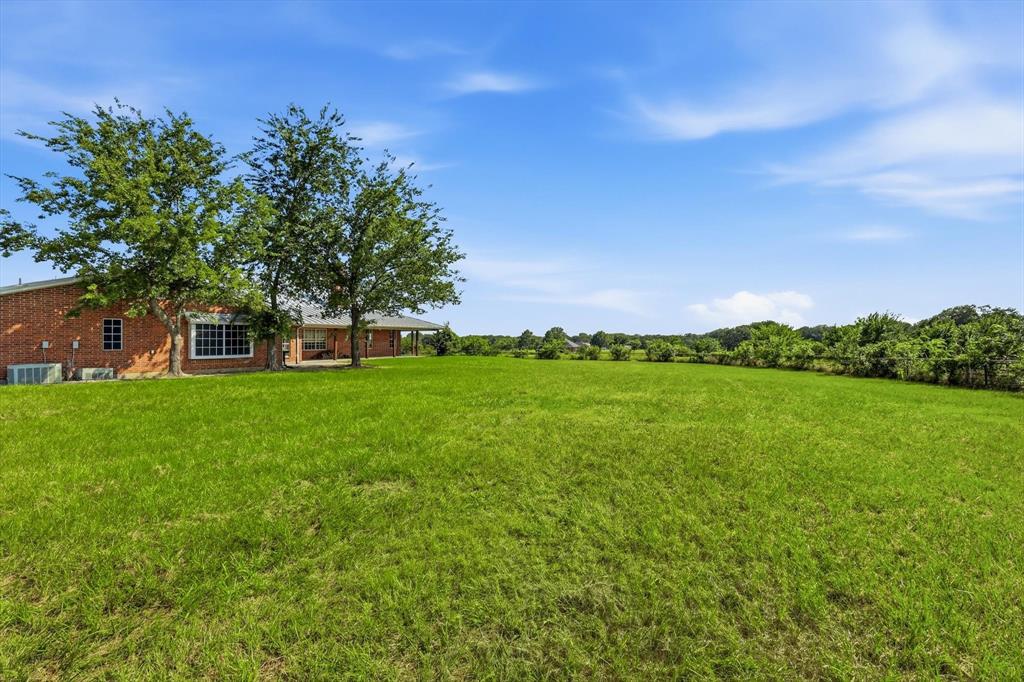 12190 Bell Road Pilot Point, TX 76258 - Photo 39 of 39 Expansive green lawn with mature trees and a brick-clad residence