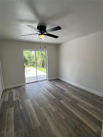 an empty room with wooden floor chandelier and windows