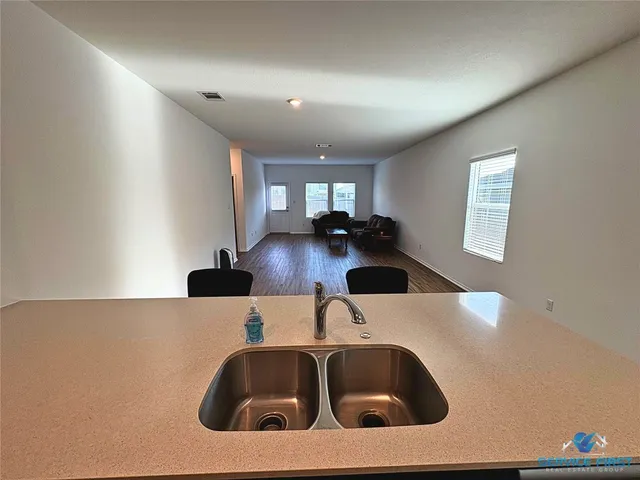 a kitchen with a sink and a stove with wooden floor