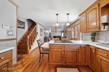 a kitchen with stainless steel appliances kitchen island granite countertop a table chairs in it and wooden floors