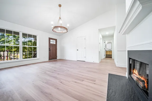 an empty room with wooden floor fireplace and windows